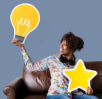 Cheerful woman showing light bulb icon on couch