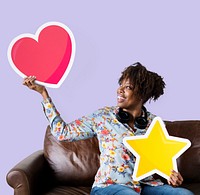 Cheerful woman showing heart icon on couch