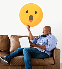 Man showing a surprised emoticon and using laptop