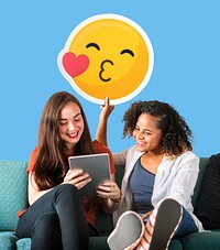 Women holding a kissing emoticon and using a tablet
