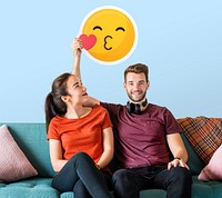Cheerful couple holding a kissing emoticon