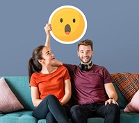 Cheerful couple holding a surprised emoticon