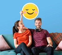 Cheerful couple holding a blushing emoticon