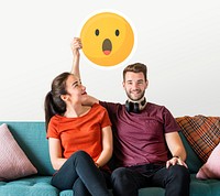 Cheerful couple holding a surprised emoticon
