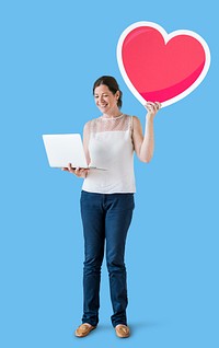 Standing woman holding a heart emoticon and a laptop<br />