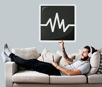 Male on a couch holding a frequency icon<br />