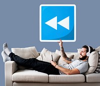 Male on a couch holding a rewind button icon