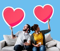 Interracial couple on a couch holding heart emoticons