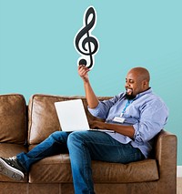 Man using a laptop and holding a musical note