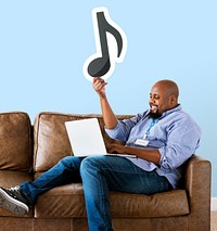 Man using a laptop and holding a musical note