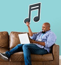 Man using a laptop and holding a musical note