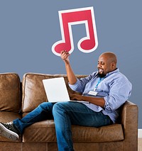 Man using a laptop and holding a musical note icon