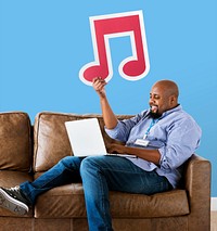 Man using a laptop and holding a musical note icon