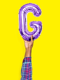 Hand holding balloon letter G