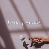 Love your self quote on a hand holding flower background