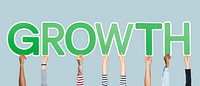 Hands holding up green letters forming the word growth