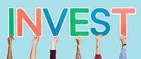 Hands holding up colorful letters forming the word invest