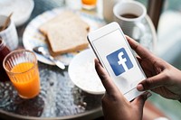 Woman using Facebook while having breakfast. BANGKOK, THAILAND, 1 NOV 2018.