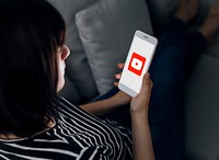 Woman sitting on a couch using Youtube application. BANGKOK, THAILAND, 1 NOV 2018.