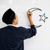 Young Muslim man drawing a muslim crescent and a star on a whiteboard