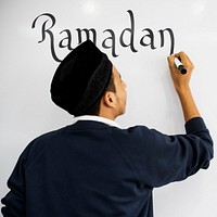 Young Muslim man writing ramadan on a whiteboard