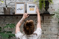 Woman adjusting Dream big photo frame on shelf