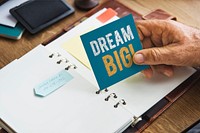 Senior hand holding a Dream big sticky note