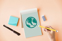 Hand drawing a green globe on a notepad