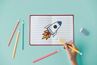 Hand drawing a rocket launch on a notebook