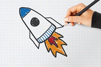 Hand drawing a rocket launch on a notebook paper