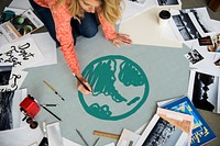 Woman drawing a green globe on a paper
