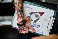 Tattooed hand holding a startup clipboard