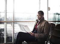 African descent man sitting reading magazine with earphones