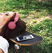 Woman lying on grass listening to music