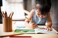 Little girl drawing in a book