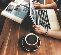 Hands with laptop on wooden table in coffee cafe