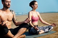 Caucasian couple meditate at the beach