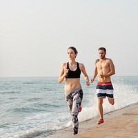Healthy young couple running by the beach