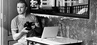 Photographer with is camera and laptop in a cafe