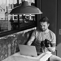 Photographer with is camera and laptop in a cafe
