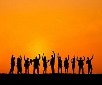 Silhouette of business people with arms raise at sunset