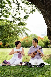 Senior Asian couple playing music in a park