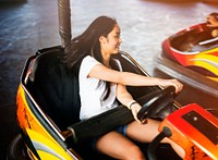 Young adult woman playing in bumper car at amusement park