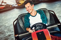 Young guy riding the bumper cars at an amusement park