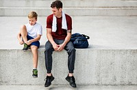 Closeup of coach sitting on step with young boy tying trainers robe