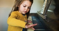 Cute and adorable little girl learning how to play a piano