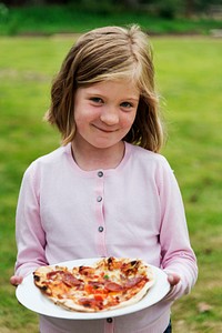 A little girl holding a plate of pizza