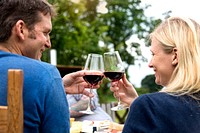 Cheerful couple raising a glass of wine in an outdoor restaurant
