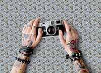 Tattooed hands holding a retro analog film camera
