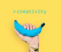 Hand with tattoo lifting blue banana with yellow background